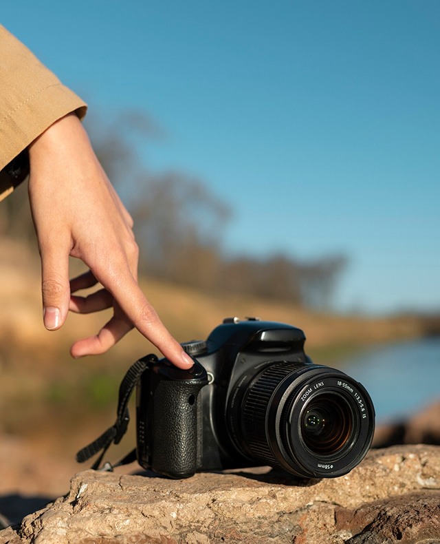 cámara sobre una roca, siendo presionada por la mano de una mujer