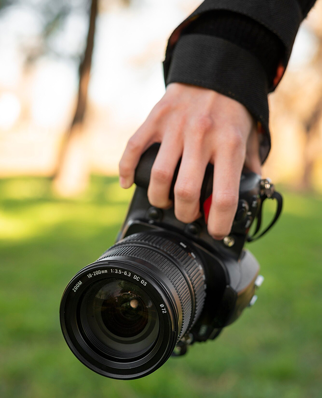 cámara sostenida por una mano, con un parque verde de fondo
